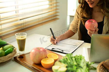 营养师坐在办公桌前，端着水果和蔬菜，制定饮食计划。