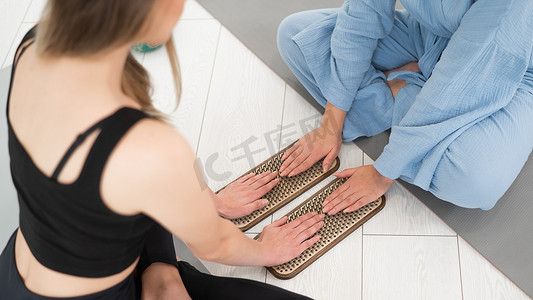两个女人坐在瑜伽垫上，双手放在苦行僧板上。