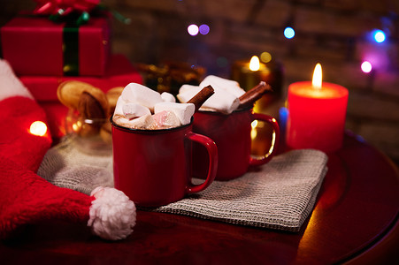 节日圣诞桌上放着红杯热巧克力可可饮料、棉花糖和肉桂