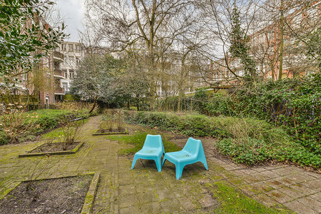 砖砌人行道上有两把蓝色椅子的花园