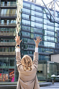 站在市中心街道外的企业女性、律师庆祝、举手和胜利、实现目标或成功的后视图