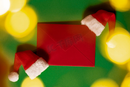 绿色背景上有空纸卡便条信封的圣诞老人帽子。