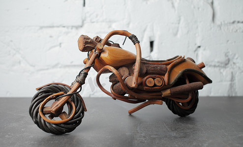 摩托车背景摄影照片_灰色背景中用木头制成的玩具摩托车