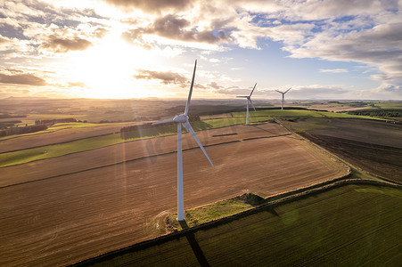 风里发电摄影照片_阳光明媚的日子里，绿色可再生能源农场的风力涡轮机