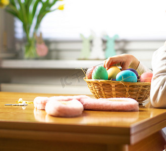 五岁的小孩在木桌上的木篮子里玩彩色复活节彩蛋。