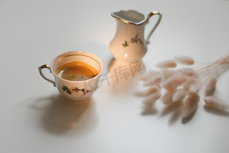 杯咖啡和牛奶壶在白色的木制背景，特写。