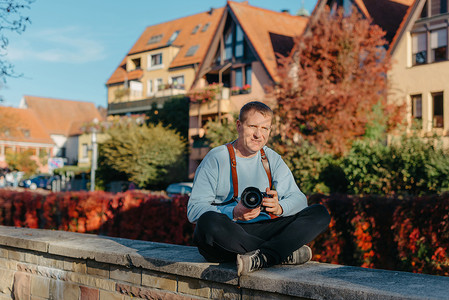 手拿照相机摄影照片_坐在老欧洲城市和拿着照相机的人。