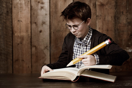 嗯，这是一个棘手的问题......小男孩戴着眼镜，用一支巨大的铅笔做作业。