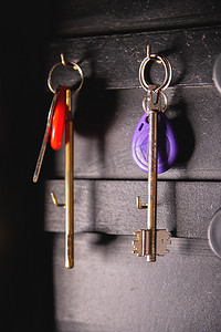 木挂衣架摄影照片_挂在木钥匙架上的门钥匙，特写