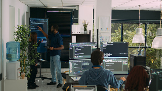 开发团队摄影照片_多元化的软件工程师团队在墙屏电视上分析代码