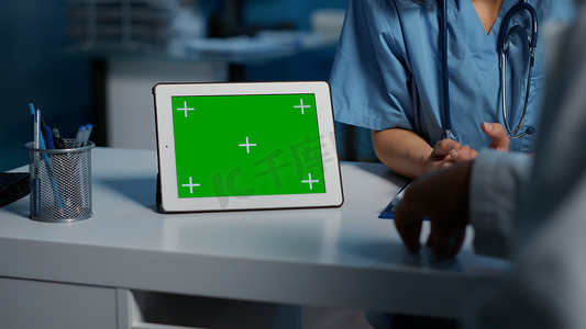 护士向医生展示带绿色屏幕的平板电脑