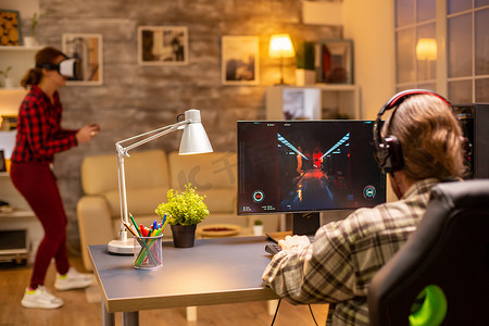 深夜在客厅玩功能强大的 PC 的专业视频游戏玩家的后视图