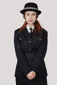 身着警服的年轻女子站在灰色背景下的肖像