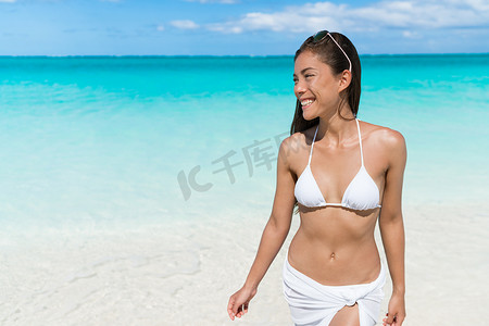 亚洲比基尼女人放松地在白色沙滩上散步