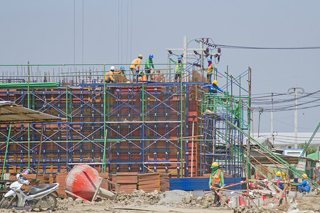 工人在篮子里安装板材，建造工厂。