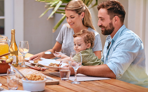 家庭、食物和午餐户外与孩子、妈妈和爸爸一起在庭院餐桌上用餐、美酒和亲密。