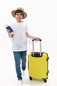全尺寸摄影照片_穿着休闲服的全尺寸旅行少年，拿着手提箱和登机牌，在白色背景中孤立地行走