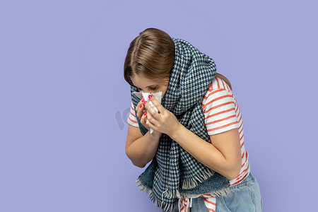裹着围巾的女人流鼻涕、发烧、打喷嚏、感冒。