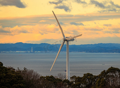 日落时在海岸上产生清洁绿色电力的风力涡轮机
