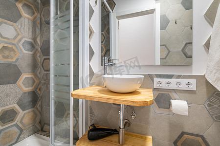 带玻璃淋浴间和水槽的浴室配有灰色多边形图案瓷砖。