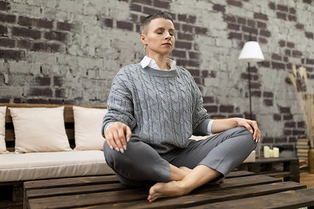 在家坐在瑜伽姿势中冥想的成年白人女性