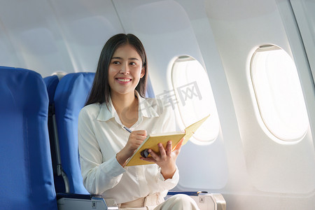 美丽的亚洲女商人在豪华飞行中快乐而微笑。
