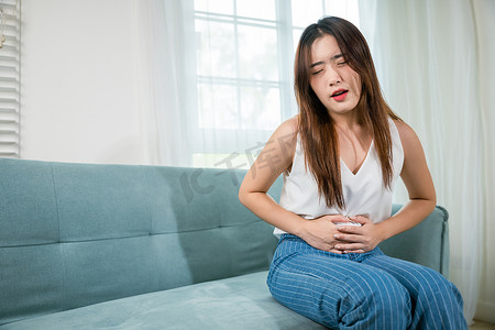 悲伤的亚洲女人闭上眼睛，她有胃痛的问题