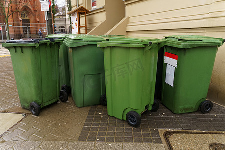 楼外人行道上的绿色塑料垃圾桶