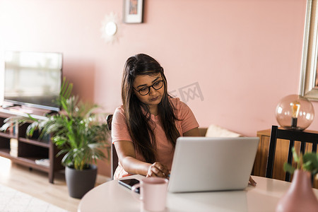 拉丁裔或印度裔女性在客厅使用笔记本电脑进行视频通话。