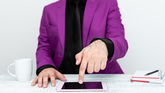 穿着粉色夹克的商人坐在桌旁，用一根手指指着手机上的重要信息。