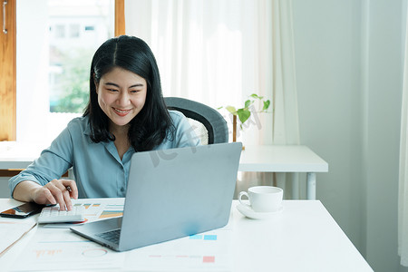财务、规划、营销和会计，亚洲员工在工作中使用文档和计算器以及计算机检查财务报表的肖像