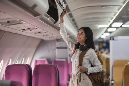 乘飞机旅行摄影照片_年轻的亚裔女性乘飞机旅行。