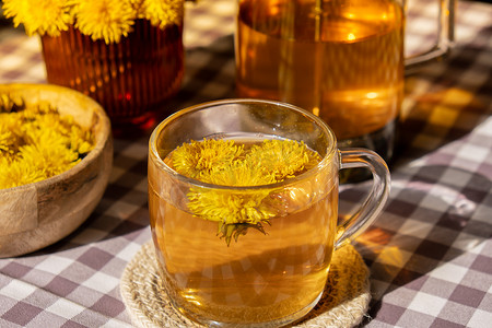 蒲公英花健康茶在玻璃茶壶和玻璃杯在桌上。
