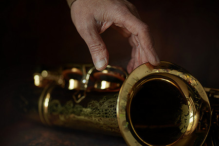 萨克斯管上的音乐家之手 - 一种古老的木制乐器，流行于古典铜管进行曲爵士民间音乐中，深受儿童和成人、业余爱好者和专业人士的喜爱。