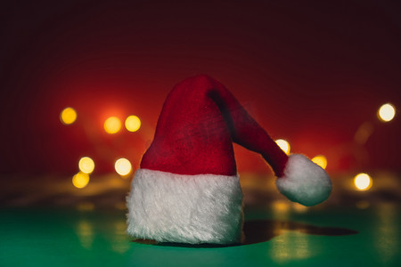 圣诞节绿色帽子摄影照片_等距绿色红色背景上的圣诞老人帽子。