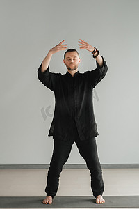 一个穿着黑色和服的男人在室内练习气功能量练习
