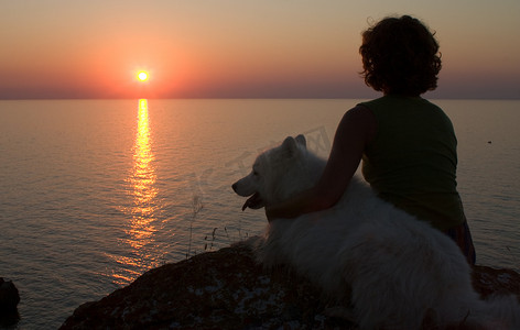女孩和狗期待着海上的日落