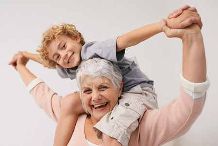 带孩子的老人摄影照片_肖像、背驮式或快乐的祖母带着孩子在家里玩耍或充满爱意地拥抱。