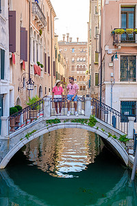 一对男女在意大利威尼斯的城市旅行中坐在威尼斯运河的一座桥上