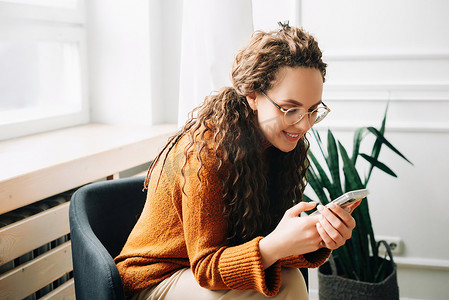 快乐的女人在手机上浏览现代应用程序 放松的女人使用手机进行网上购物 年轻女人在智能手机上发短信和浏览互联网。