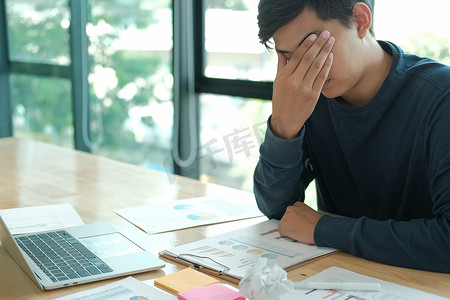 男人感到疲倦，沮丧，因为桌上皱巴巴的碎纸辛勤工作而感到压力。