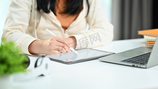 坐在工作场所的女性员工在数字平板电脑上搜索在线信息的剪影