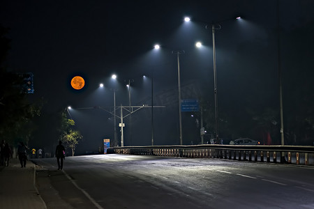 超级巨无霸摄影照片_清晨空荡荡的街道上的超级月亮图像。