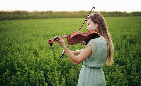 拉小提琴摄影照片_拉小提琴的头发松散的浪漫女人。