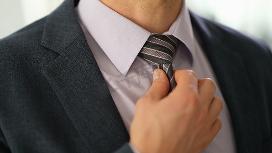 穿着西装的商人在衬衫上拉直领带，手特写