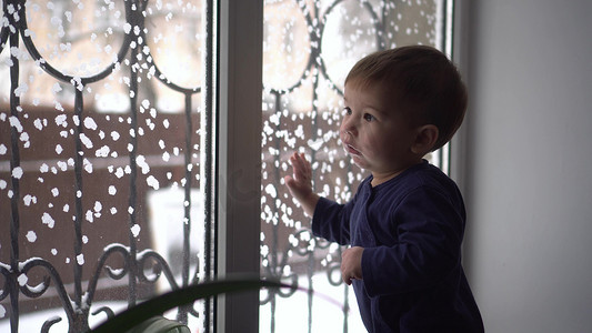 一个小孩站在窗台上，看着窗外。