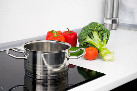 带感应炉的现代厨房中的锅和蔬菜