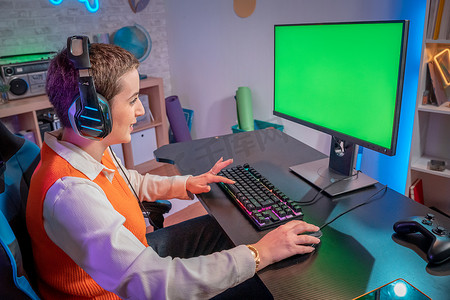 职业游戏玩家在游戏霓虹灯家庭工作室中播放带有绿屏模型显示的视频游戏