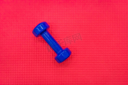 健身房红地板背景下的蓝色哑铃健身举重器材