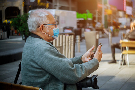 由于纽约男子用智能手机流行冠状病毒，人们在户外戴着防护面罩
